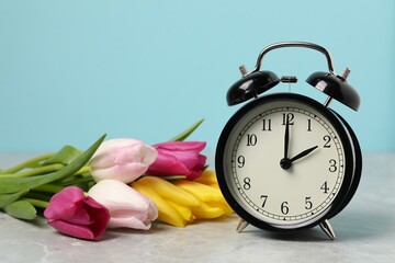 Aufkleber - Spring time. Alarm clock and beautiful tulips on grey marble table against light blue background