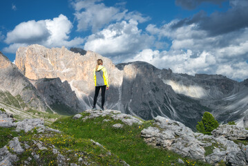Wall Mural - girl on the hill with yellow flowers and green grass in beautiful alpine mountain valley at sunset i
