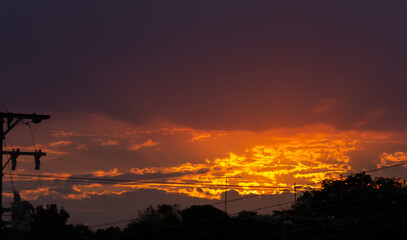 Wall Mural - sunset over the city with orange sky and silhouette of electric pole