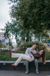 © ibilyk13 - Happy couple in love enjoying a playful moment in the city park. A young man sitting on a bench holding his girlfriend in his arms as they smile at each other. Urban nature, romance, and joy.