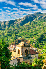 Wall Mural - View of mediterranean italian town in mountain valley of Sicily, Italy. Old town in a valley among green mountains with ancient church and vintage roofs of buildings in beautiful evening sunset light