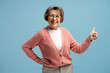 © Maria Vitkovska - Happy senior woman showing thumbs up gesture and smiling on blue background