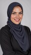 © SimpleDesignStudio - Young Middle-Eastern Woman in a Dark Hijab and Black Top, Smiling Against a Neutral Background, Radiating Confidence and Grace