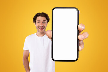 Poster - Mobile App Advertisement. Handsome Excited Man Showing White Empty Smartphone Screen Recommending App Posing Over Orange Studio Background, Smiling To Camera. Check This Out, Cellphone Display Mock Up