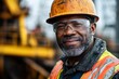 © SY - Close-up portrait of a mature, smiling construction worker wearing a hard hat and safety glasses. This image depicts skilled labor and workplace safety.