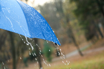 Wall Mural - Open blue umbrella under pouring rain outdoors, closeup. Space for text