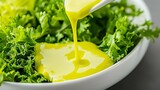 Fresh green salad being drizzled with vibrant yellow dressing in a bowl