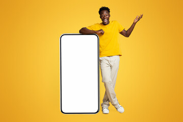 Poster - Surprised Young Black Guy Standing Next To Big Smartphone With White Screen, Emotional African Man Raising Hand In Excitement, Demonstrating Copy Space For Mobile App Advertisement Or Design, Mockup