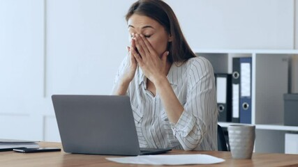 Poster - A young woman focuses on her laptop while seated at a stylish office desk. The workspace is well-lit, featuring organized files and a cup beside her, indicating a productive atmosphere.