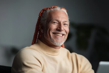 Smiling man with stylish long hair sitting comfortably in a modern workspace while engaging with technology