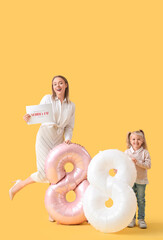 Wall Mural - Little girl with her mother, festive postcard and balloons in shape of figure 8 on yellow background. International Women's Day