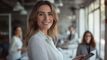 Poster - A confident business leader smiles warmly as she engages with her colleagues in a contemporary office space filled with natural light. The atmosphere is vibrant and interactive