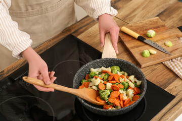 Wall Mural - Young woman roasting tasty vegetables in kitchen