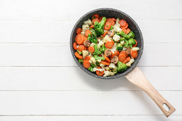 Canvas Print - Frying pan with tasty roasted vegetables on white wooden background