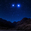 © Fragton - Stars Gleaming Above a Rugged Mountain Valley Landscape in the Nighttime Sky With Brilliant Lights.