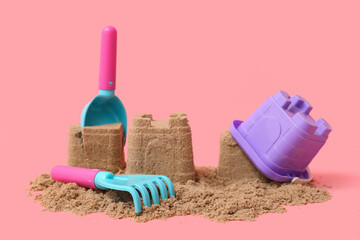 Beautiful sand castle and beach toys on pink background