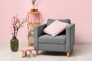 Wall Mural - Interior of living room with armchair, vase of flowers and Easter cakes on shelving unit near pink wall