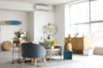 Wall Mural - Blurred view of living room with sofa, shelf unit and green plants