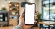 © Rhony - Close-up, hand holding smartphone with empty screen mockup in coffee store interior