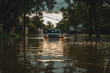 © mat - A stranded car surrounded by floodwater on a rainy day with ample copy space. Overcast light. Suburban road background.