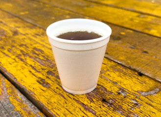 Wall Mural - A plastic cup of coffee sits on a wooden table