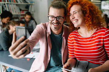 Canvas Print - Friendly happy multiethnic coworker male and female having fun with smartphone, working together