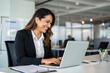 © Sadaqat - Smiling Female HR Manager Using Laptop at Work Desk in Corporate Office'