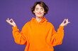 © ViDi Studio - Young happy Caucasian woman she wearing orange hoody casual clothes hold spreading hands in yoga om aum gesture relax meditate try to calm down isolated on plain purple background. Lifestyle concept.