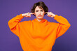 © ViDi Studio - Young sad unhappy Caucasian woman wear orange hoody casual clothes cover ears with hands fingers do not want to listen scream isolated on plain purple background studio portrait. Lifestyle concept.