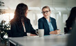 © Flamingo Images - Two young businesswomen talking during a boardroom meeting in an office.