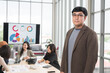 © PhugunStock - Asian male businessman poses at camera holding a tablet. Businessman brainstorming and discussing analysis, innovation and collaboration. online business Modern sales techniques and strategic planning