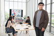 © PhugunStock - Asian male businessman poses at camera holding a tablet. Businessman brainstorming and discussing analysis, innovation and collaboration. online business Modern sales techniques and strategic planning