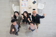 © PhugunStock - Top view of business people, Asian man and woman looking at camera, hands raised, happy, talking about analysis, innovation and collaboration. Online business, sales techniques, strategic planning