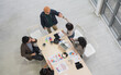© PhugunStock - Top view: Happy Asian businessmen and women, holding hands, brainstorming and talking about analysis, innovation, and collaboration. Online business, sales techniques, strategic planning