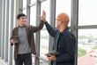 © PhugunStock - Asian male businessman Tag a friend's hand happy smile Holding a tablet, talking about analytics, innovation, and collaboration. Online business, sales techniques, strategic planning