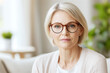 © Vasili - A close-up portrait of an older woman with glasses, sitting in a well-lit office and looking confidently at the camera. She represents professionalism and calmness in the workplace.