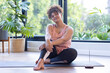 © Wavebreak Media - Sitting on yoga mat, plus size woman smiling and relaxing after workout, at home, at home