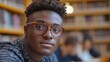 © MKS - A dedicated African American millennial with glasses, writing down information from a book in a café, getting ready for a test or exam, portraying a serious attitude as he studies or works in a