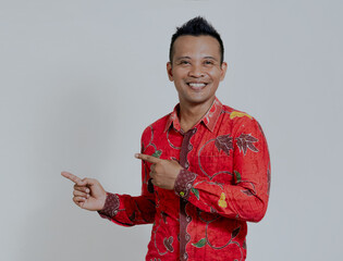 Happy asian man pointing away at empty space with two fingers isolated over white background.