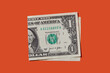 © Tetra Images - Folded one dollar bill on orange background