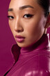 © SHOTPRIME STUDIO - Fashionable brunette asian woman in a purple leather jacket posing on a pink background
