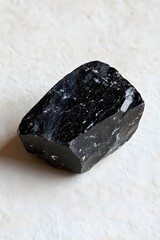 Poster - Glossy obsidian stone on textured white surface a study in contrast and natural beauty