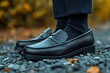 © Graph Squad - Classic black leather loafers on pebbles paired with dark socks A timeless footwear choice for a polished and sophisticated look