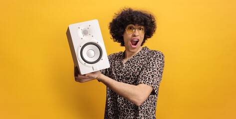 Wall Mural - Young man with curly hair holding a music speaker