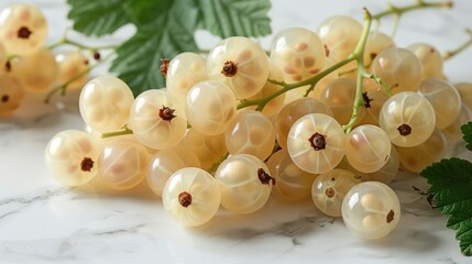 Poster - A cluster of pale yellow currants resting on a marble surface with green leaves.