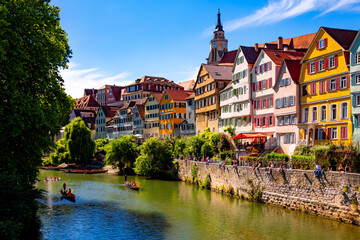 Tuebingen popular university town in southern Germany. “Neckarfront“ with colorful facades, church (Stiftskirche) and poled boats (Stocherkahn) on the River Neckar on a sunny summer day. 