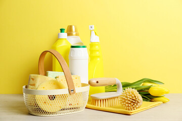 Wall Mural - Spring cleaning. Detergents, supplies and tulips on white wooden table against yellow background