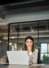 Wall Mural - Smiling middle aged 40s professional business woman in office, portrait. Happy mature mid age professional businesswoman executive wearing suit looking at camera at work with laptop sitting at desk.