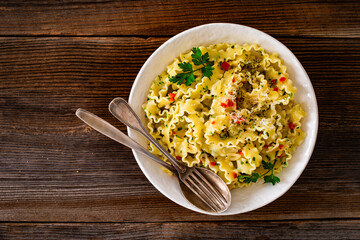 Wall Mural - Pasta with garlic, parsley and pepperoncino on wooden table. Boiled mafaldine noodles. Spaghetti aglio olio e peperoncino on wooden background