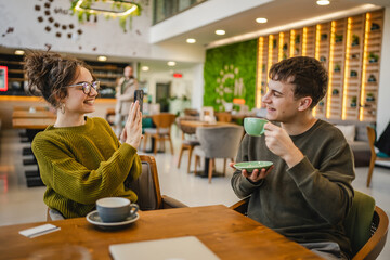 Wall Mural - girlfriend use mobile phone to take a photo of her boyfriend at cafe